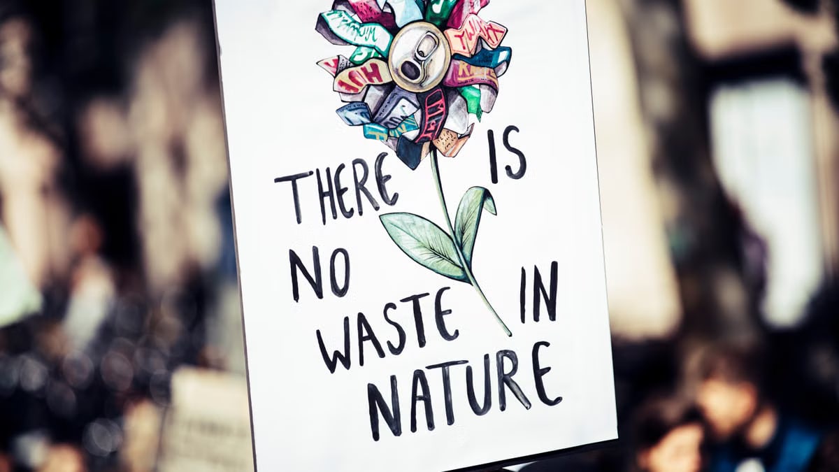 Protest sign featuring a flower made from recycled materials promoting environmental conservation.