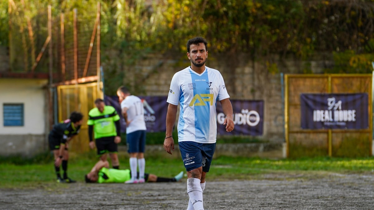 Soccer player walks on field with injured teammate